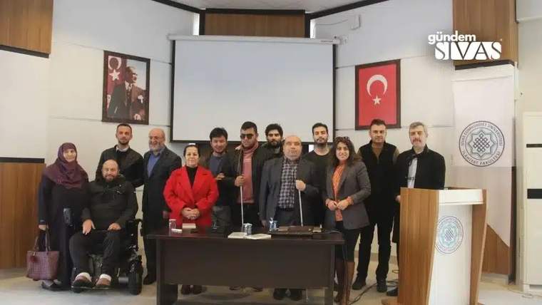İlahiyat Fakültesi'nde bir grup insan, masanın etrafında toplanmış, fotoğraf çekiliyor.