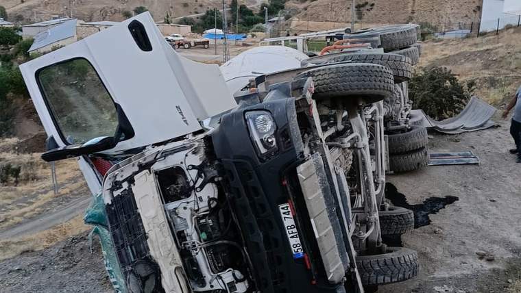 Yol kenarında yan yatmış beton mikserinin kabini ve alt kısmı, çevresine saçılmış parçalarla görülüyor.