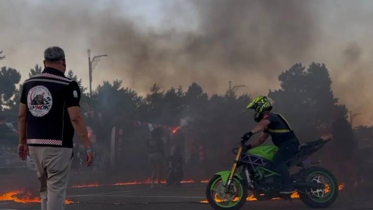 Alevlerin etrafında dönen bir motosikletli, festival alanında gösteri yapıyor.