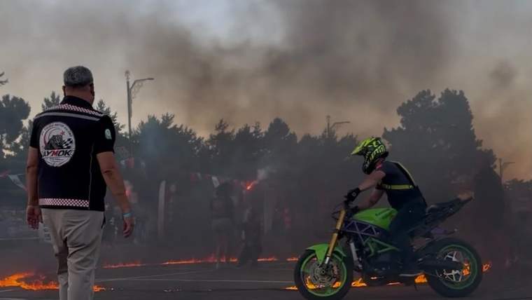 Alevlerin etrafında dönen bir motosikletli, festival alanında gösteri yapıyor.