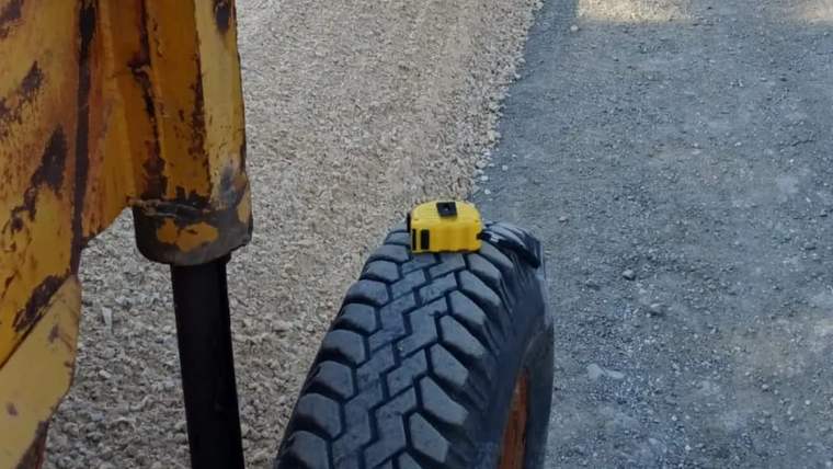 Asfalt serimi yapılan yolda, sarı iş makinesinin bir bölümü ve yol yüzeyindeki farklı kaplamalar görülüyor.