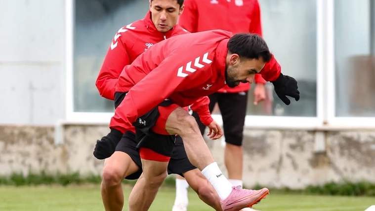 Kırmızı forma giymiş futbolcular, antrenman sahasında çalışıyor.