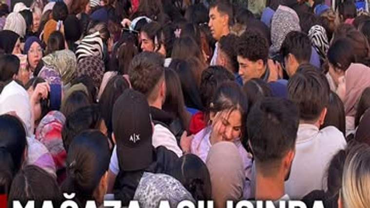 Mağaza girişinde çok sayıda kişinin birbirine yakın durduğu yoğun kalabalık görülüyor.