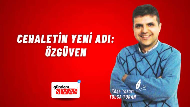 Mavi kazak giymiş bir kişi, kırmızı arka planda kollarını kavuşturmuş şekilde duruyor.
