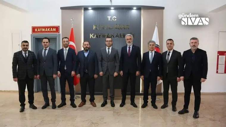 Kaymakamlık binasında, duvarında “T.C. Kaymakamlığı” yazan bölüm önünde sekiz kişi yan yana duruyor.