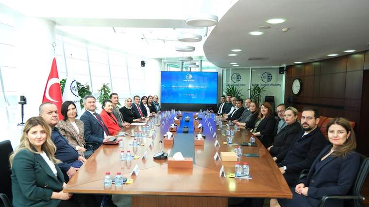 Türk bayrağının bulunduğu salonda, uzun masa çevresinde oturan kalabalık bir grup toplantı yapıyor.