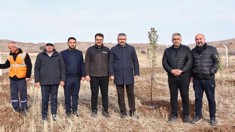 Sivas OSB'de ağaç diken bir grup insan, arka planda kurak bir arazi görünmekte.