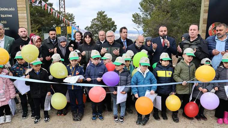 Renkli balonlar tutan çocuklar, kurdele kesme töreninde bir araya gelmiş.