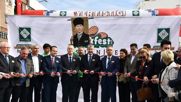 Üzerinde “Yer Fıstığı Festivali” yazan pankart önünde, kurdele kesen bir grup kişi duruyor.