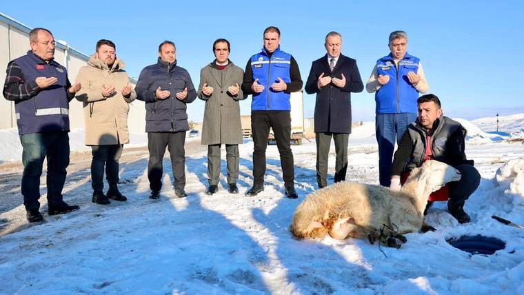 Kar yağışı sonrası bir grup insan, karla kaplı alanda dua ederken, önlerinde bir koyun yatıyor.