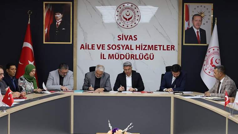 Sivas Aile ve Sosyal Hizmetler İl Müdürlüğü'nde toplantı yapan kişiler, masada belgelerle oturuyor.