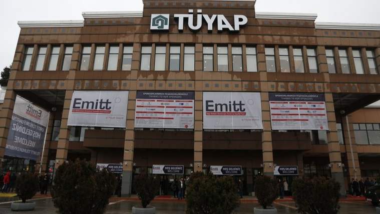 TÜYAP yazılı fuar merkezi girişinde, cepheye asılmış EMITT afişleri ve önünde saksı bitkileri görülüyor.