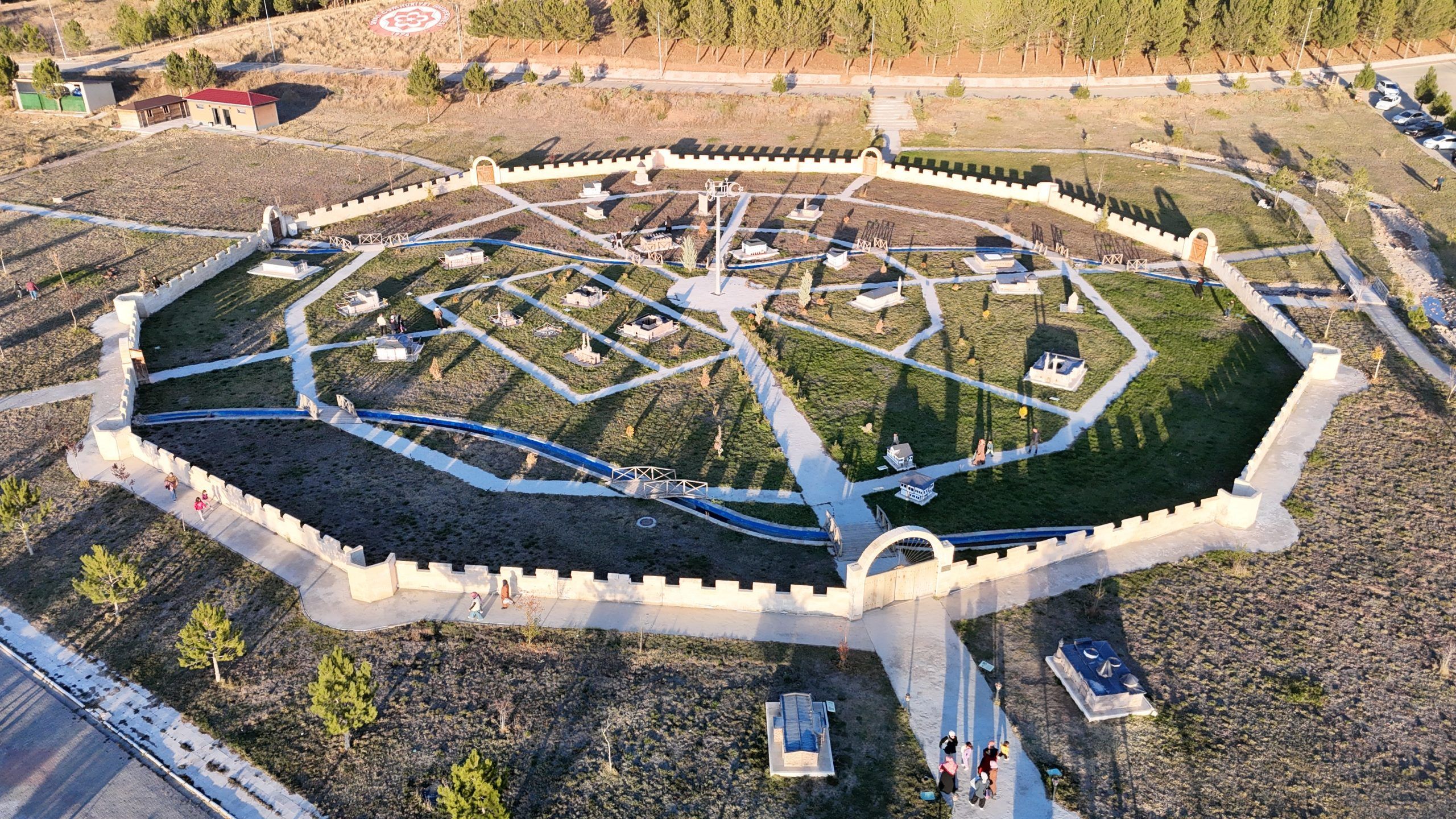 Havadan görünüşte, taş duvarlarla çevrili geometrik yürüyüş yolları ve yeşil alanlar bulunan düzenli bir bahçe görülüyor.