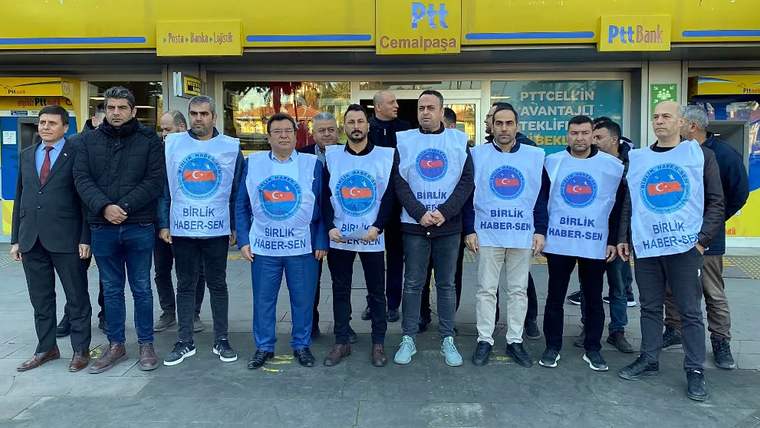 PTT ve PTTBank tabelalarının bulunduğu bina önünde, beyaz önlükler giyen bir grup kişi yan yana duruyor.
