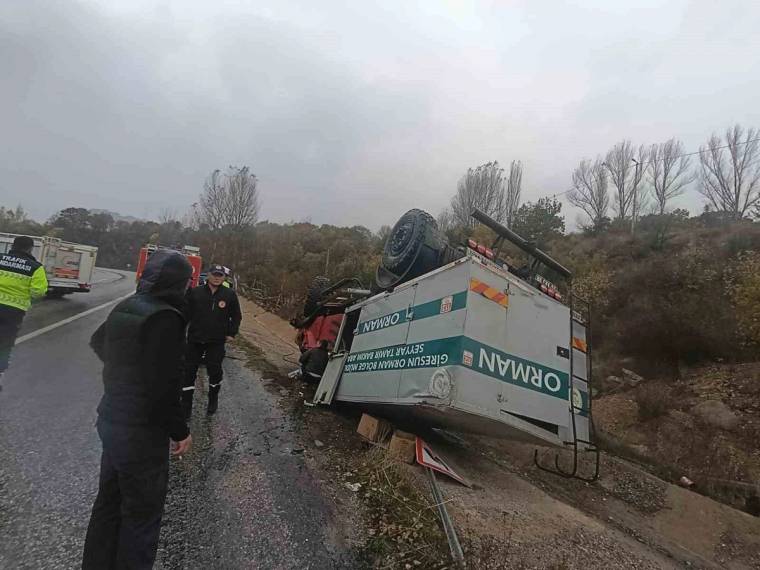 Yol kenarında yan yatmış bir minibüs, çevresinde duran üç kişi ve devrilmiş yol bariyeri görülüyor.