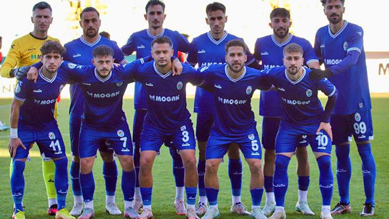 Mavi formasıyla bir futbol takımı, sahada poz veriyor.