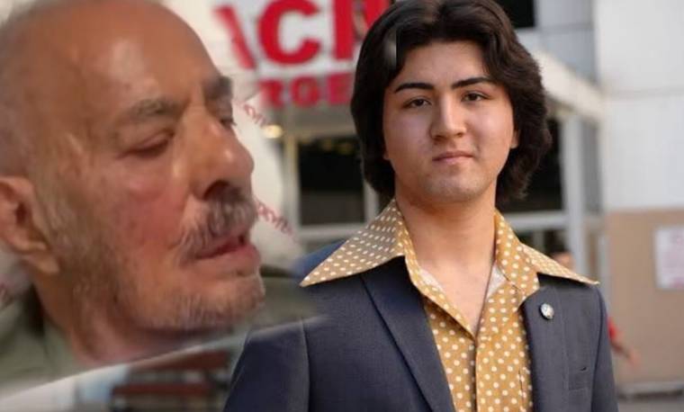 Bina girişinin önünde takım elbiseli genç bir erkek ve yanında yaşlı bir erkeğin büyük portresi görülüyor.