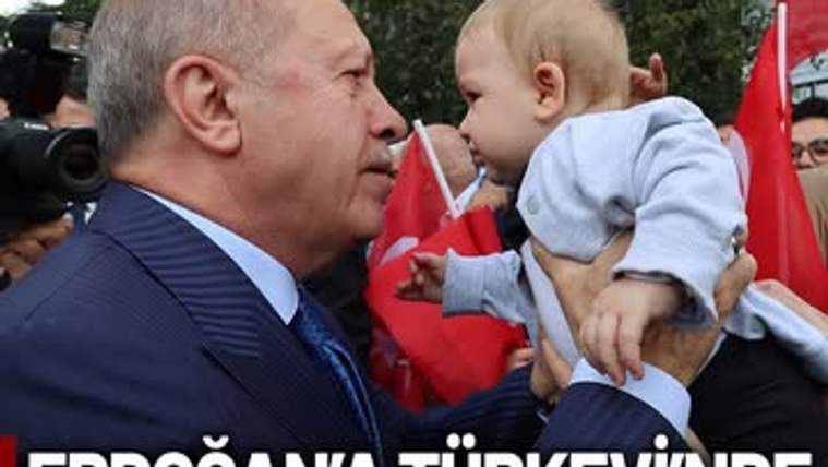 Cumhurbaşkanı Erdoğan, bir bebekle yüz yüze gelerek konuşuyor, arka planda Türk bayrakları var.