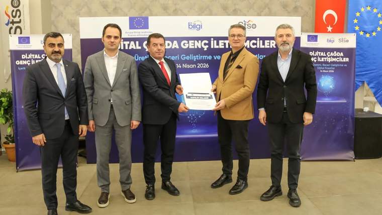 Beş erkek, üzerinde dijital iletişim yazıları bulunan pano önünde bir belgeyi birlikte tutuyor.