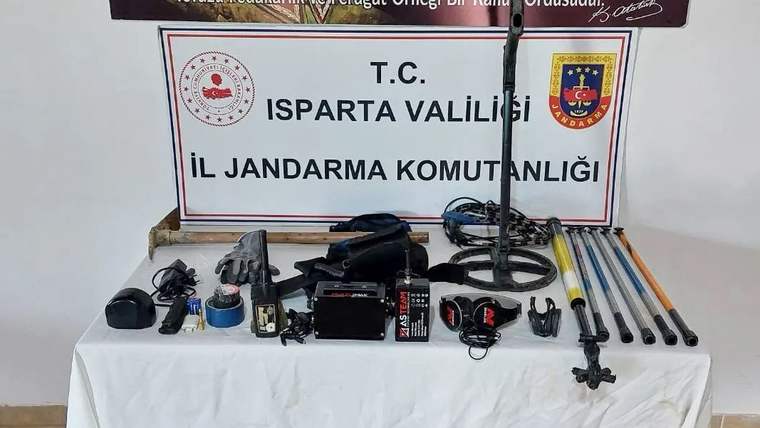 Üzerinde Isparta Valiliği İl Jandarma Komutanlığı yazan panonun önünde çeşitli elektronik cihazlar ve uzun çubuklar sergileniyor.
