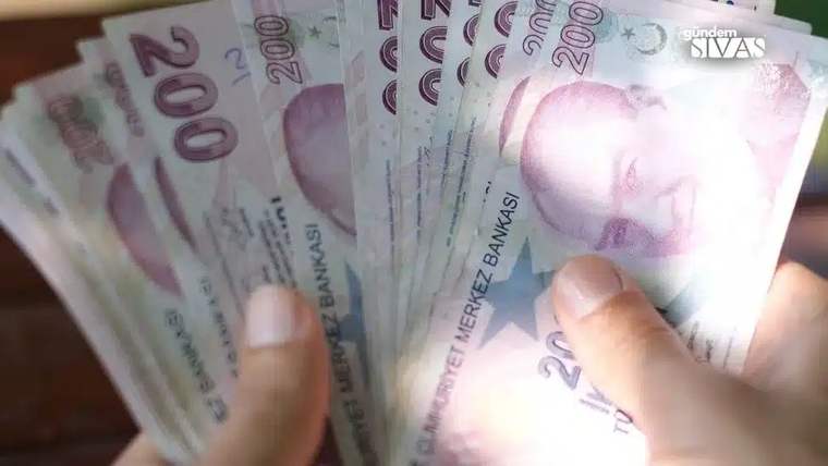 Bir kişinin elleri, üzerinde 200 lira yazılı Türk lirası banknotlarını yelpaze biçiminde tutuyor.