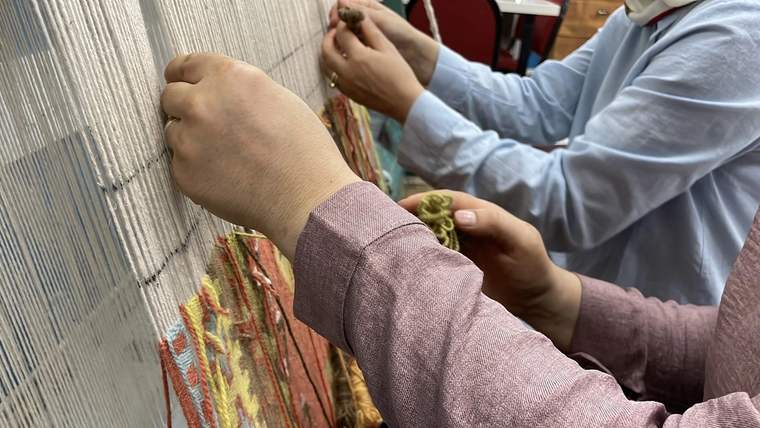İki kişinin el dokuma tezgahında kilim dokuduğu bir an.