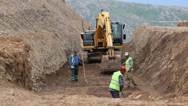 Şantiyede çalışan işçiler, kazı yapılan alanda iş makineleriyle birlikte çalışıyor.