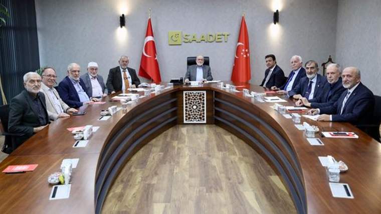 Saadet yazısının bulunduğu salonda, Türk bayrakları önünde uzun toplantı masasında oturan kişiler