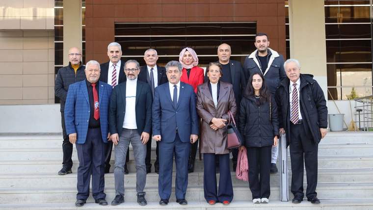 Bir grup insan, bir binanın önünde toplu halde poz veriyor.