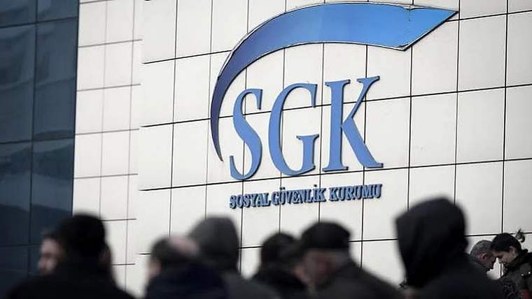 Sosyal Güvenlik Kurumu binasının duvarındaki SGK logosu önünde bir grup insan görülüyor.