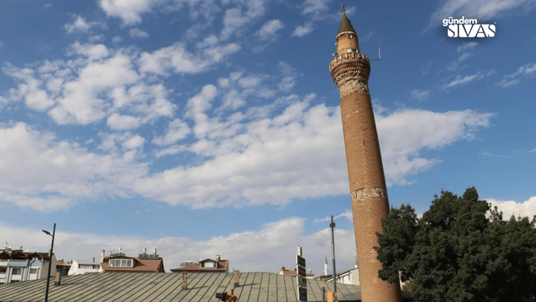 Tarihi bir minare, mavi gökyüzü ve bulutlar arasında yükseliyor.