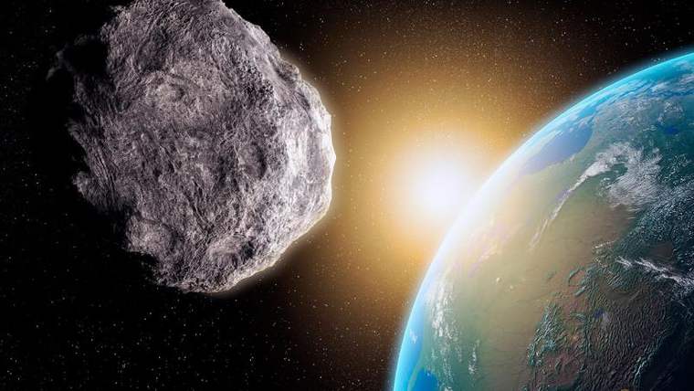 Uzay boşluğunda büyük, kayalık bir asteroit, Güneş ışığı önünde Dünya'nın mavi ve yeşil yüzeyine yakın duruyor.