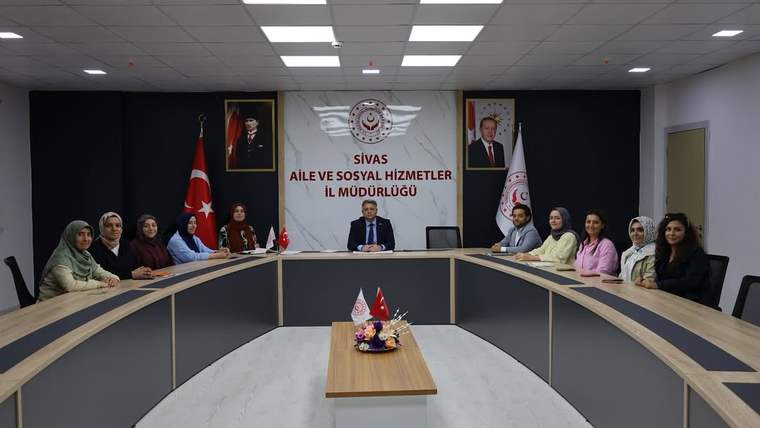Toplantı masası çevresinde oturan kişiler, Türk bayrağı ve kurum yazılı panonun önünde görülüyor.