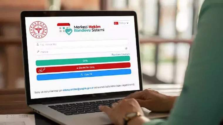 Dizüstü bilgisayar ekranında Merkezi Hekim Randevu Sistemi giriş sayfası açıkken bir kişi klavye kullanıyor.