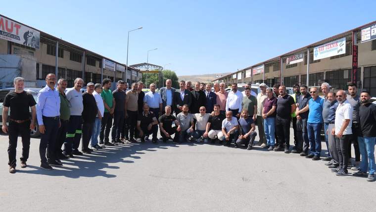 Sivas'ta sanayi esnafıyla bir araya gelen kalabalık bir grup, güneşli bir günde poz veriyor.