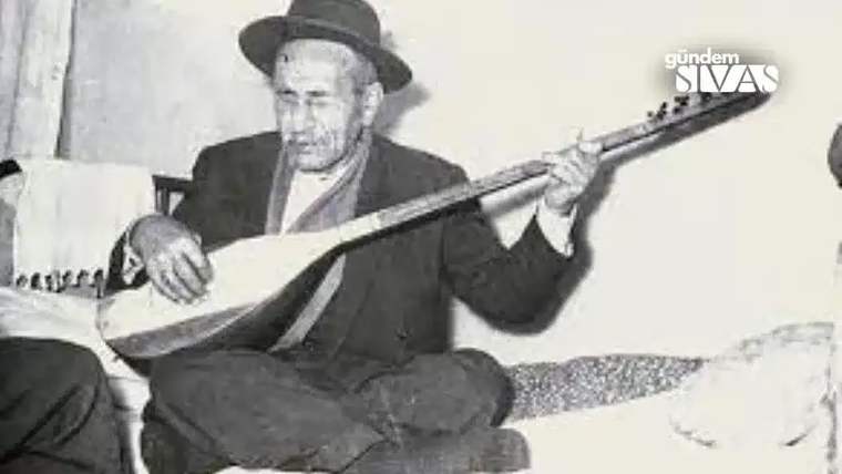 Bir adam, oturmuş bir bağlama çalıyor, üzerinde şapka var.
