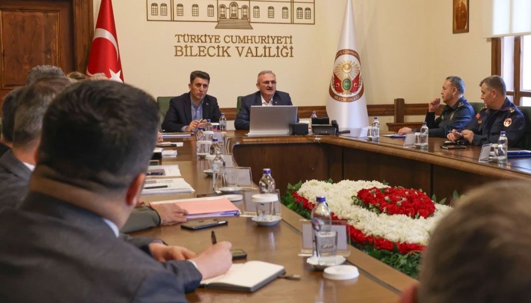 Türkiye Cumhuriyeti Bilecik Valiliği yazılı salonda, toplantı masası çevresinde görevliler oturuyor.