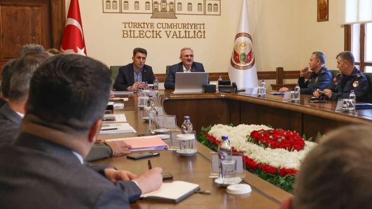 Türkiye Cumhuriyeti Bilecik Valiliği yazılı salonda, toplantı masası çevresinde görevliler oturuyor.