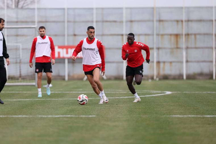 Futbol sahasında üç oyuncu, bir topun peşinden koşarken antrenman yapıyor.