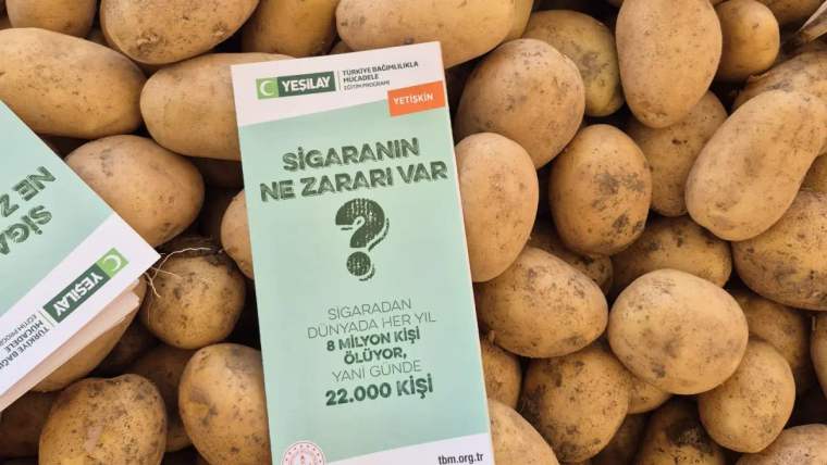 Cuma Pazarı'nda patateslerin üzerinde, sigaranın zararlarını sorgulayan bir broşür yer alıyor.