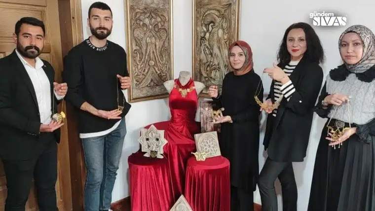 Divriği Ulu Cami motifli takıların sergilendiği bir alanda, beş kişi takıları tutarak poz veriyor.