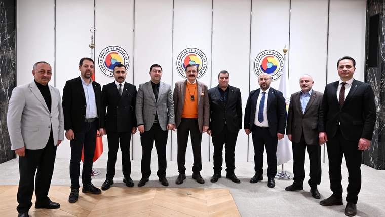 Dokuz erkek, duvarında dairesel logolar bulunan bir binanın girişinde yan yana poz veriyor.