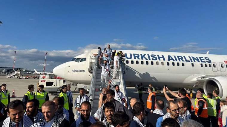 Türk Hava Yolları uçağının merdivenlerinden inen kişiler, apron görevlileri ve kalabalık arasında görülüyor.