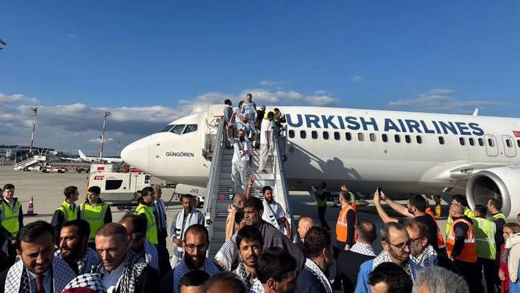 Türk Hava Yolları uçağının merdivenlerinden inen kişiler, apron görevlileri ve kalabalık arasında görülüyor.