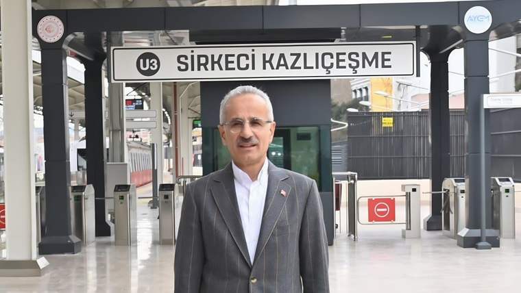 “U3 Sirkeci Kazlıçeşme” tabelasının önünde, takım elbiseli bir kişi turnikelerin yanında duruyor.