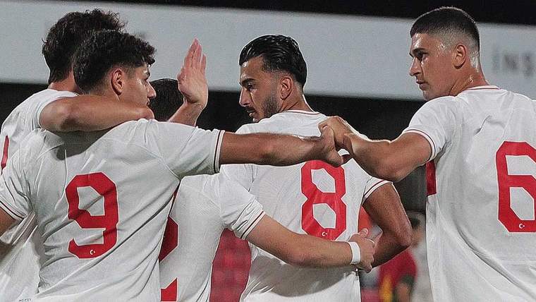 Beyaz formalar giymiş futbolcular, bir arada kutlama yapıyorlar.