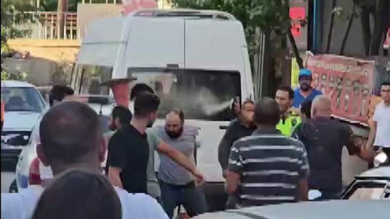 Sokakta beyaz minibüs çevresinde toplanan kişiler arasında bir adamın kollarından tutulduğu görülüyor.