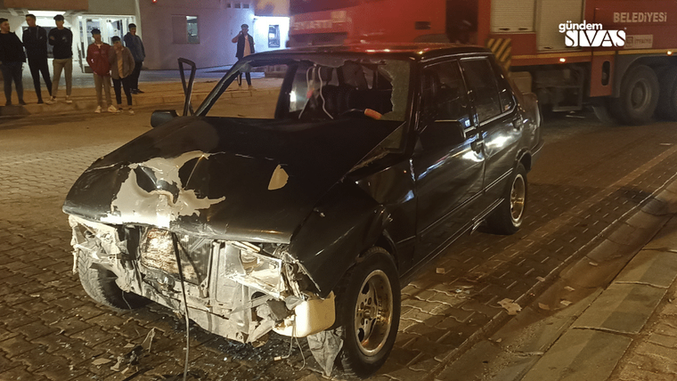 Kaza yapmış siyah bir otomobil, ön kısmı hasar görmüş halde yolda duruyor.