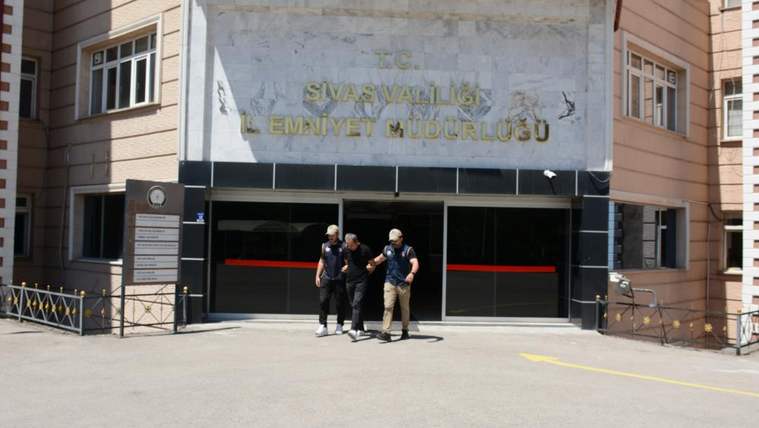 Üzerinde Sivas Valiliği İl Emniyet Müdürlüğü yazan binanın girişinde üç kişi yan yana yürüyor.