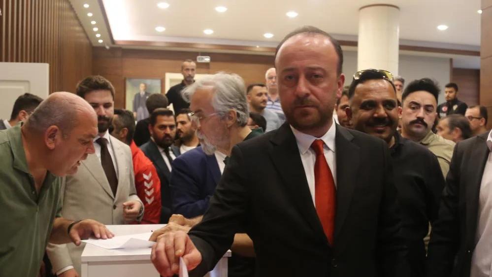 Kongrede oy kullanan bir adam, arka planda kalabalık bir grup yer alıyor.